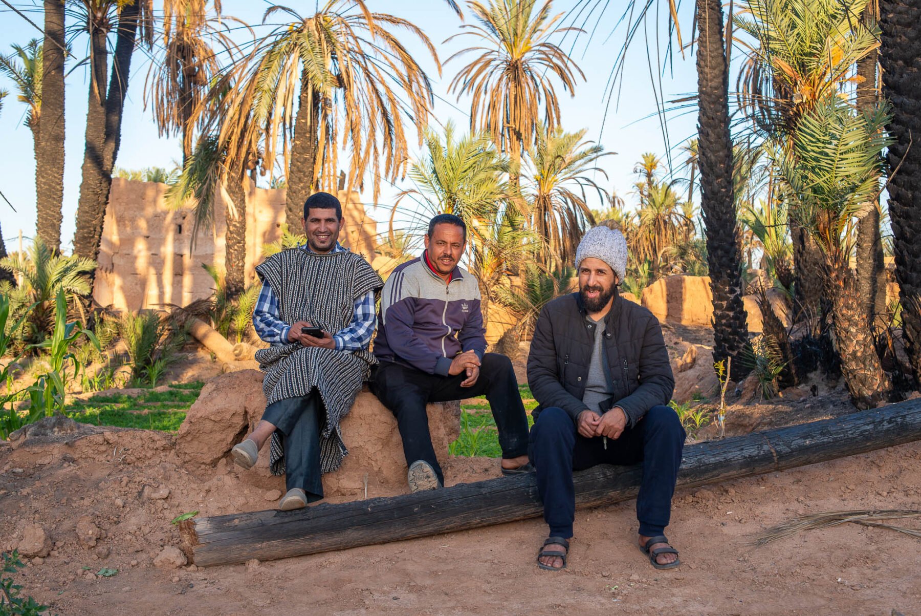 a group of men sitting under palmtrees